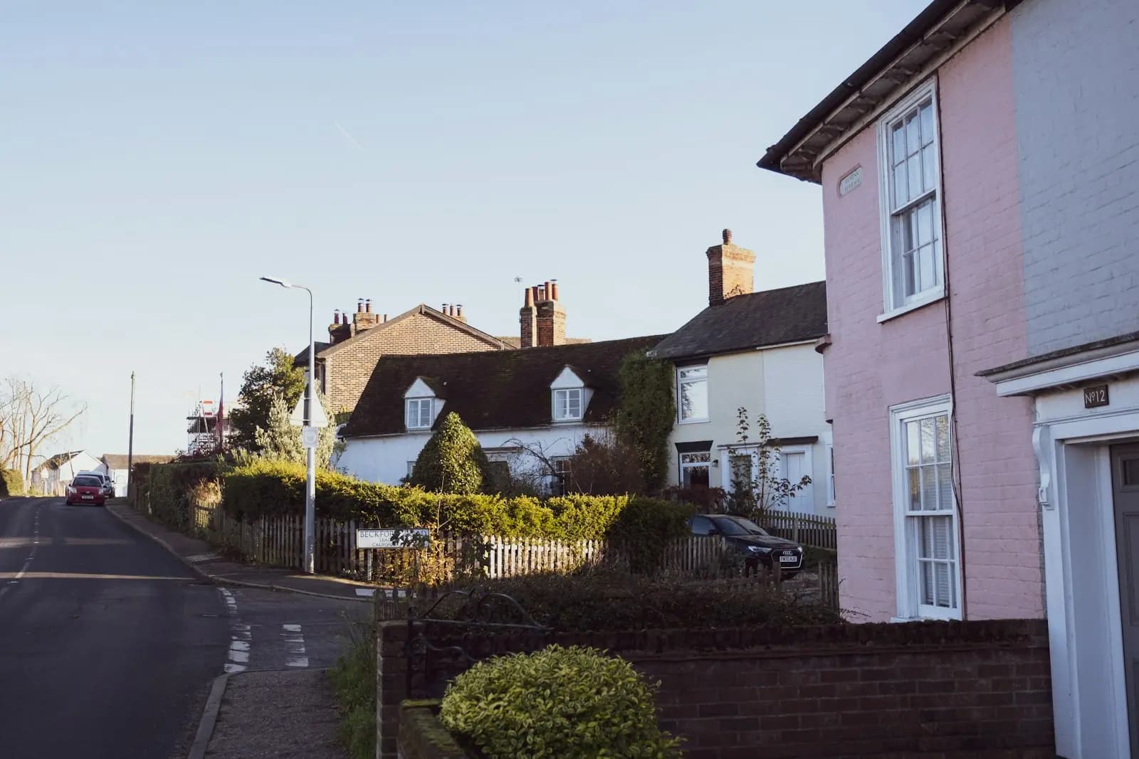 A residential street in Mistley, Essex, at sunset, with a row of brick and rendered houses along a pavement and parked cars
